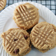 Close up of soft 3 ingredient peanut butter cookies with fork marks on top on a white plate.