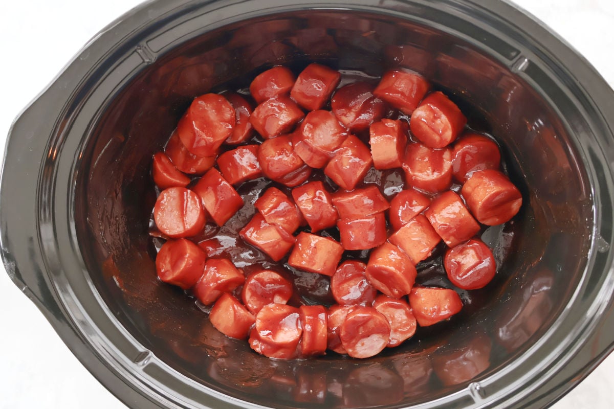 Kielbasa coated with bbq sauce cooking in the slow cooker.