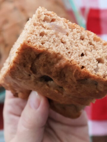 Slice of apple spice cake made with spice cake mix and apple pie filling above the baking pan full of freshly baked are you kidding me cake.