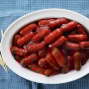 Little smokies with bbq sauce and chilli sauce in a serving dish.