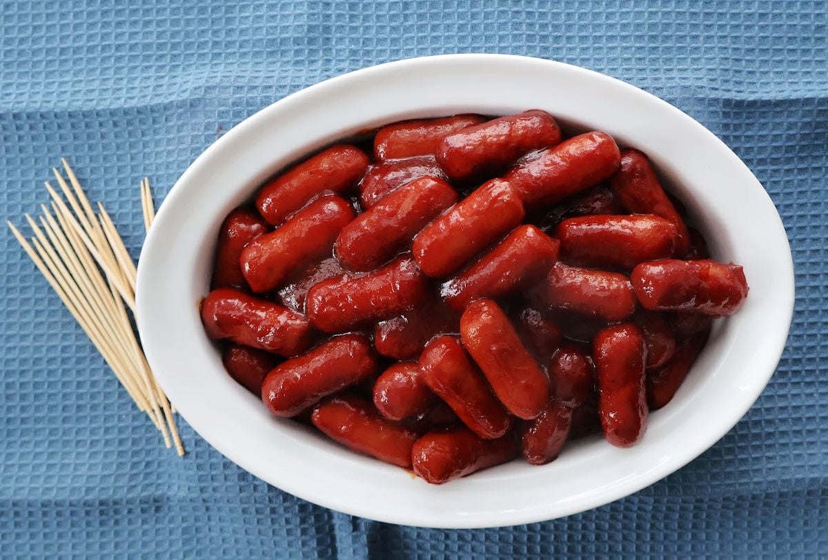 Little smokies with bbq sauce and chilli sauce in a serving dish.
