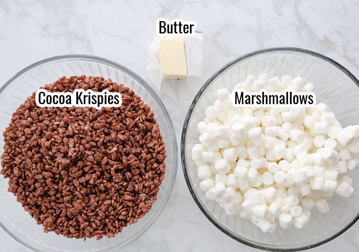 Ingredients for chocolate Rice Krispies treats including chocolate cereal, marshmallows, butter, and chocolate frosting.