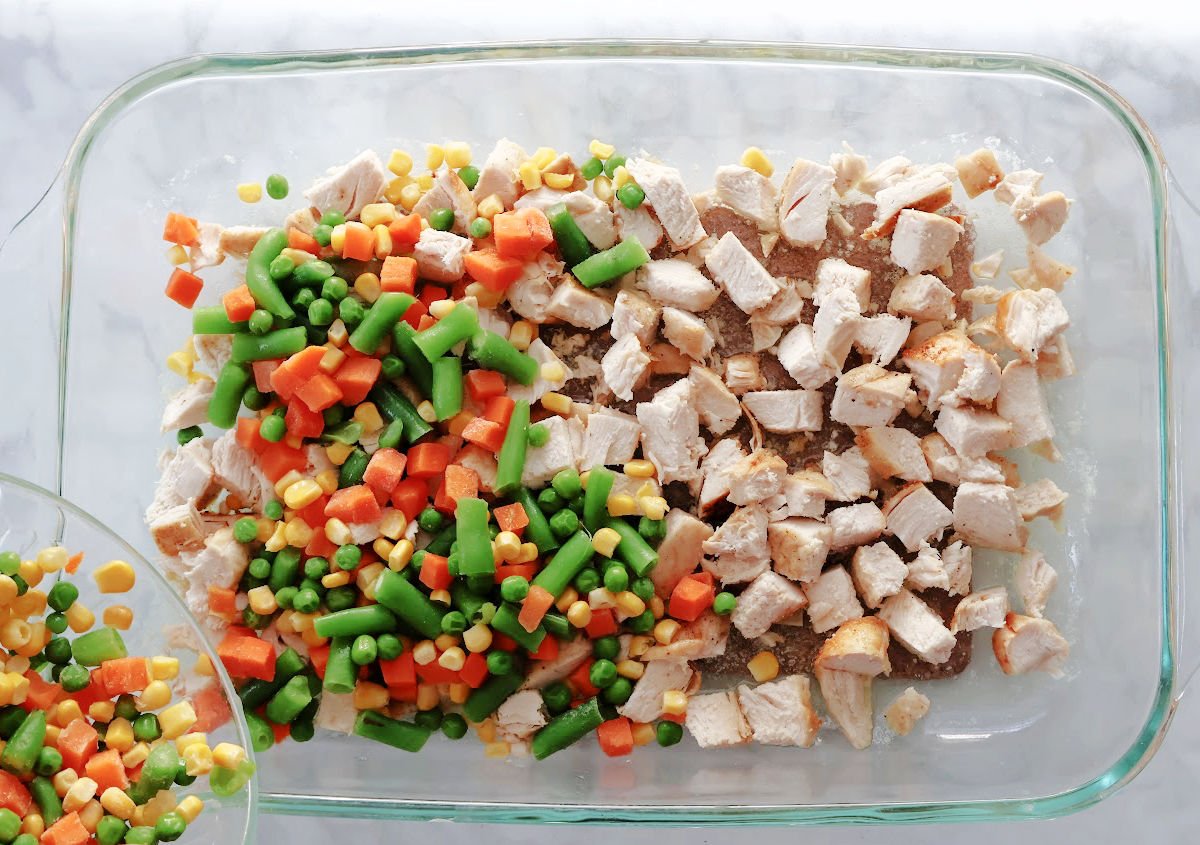 Layers of melted butter, cubed chicken and frozen veggies are the base of this chicen cobbler (in a 9 x 13 baking dish).