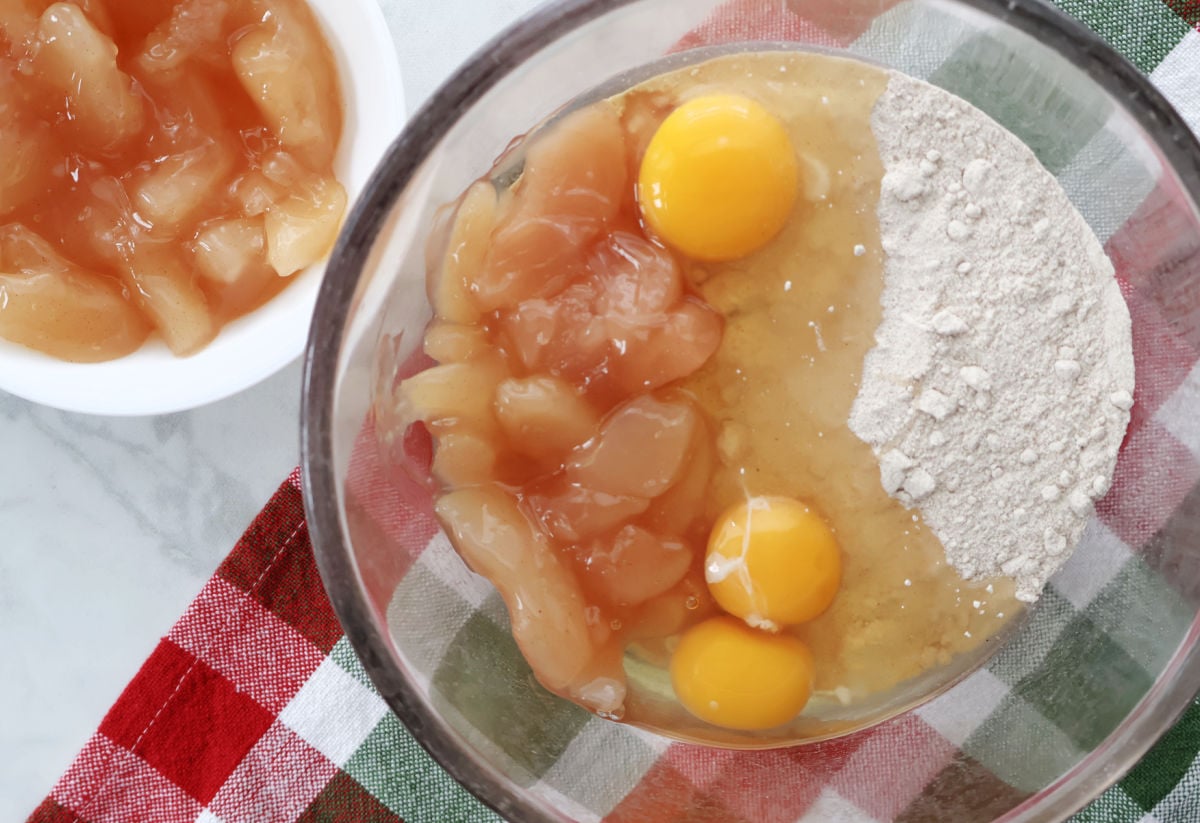 Spice cake mix, apple pie filling, and eggs mixed together in a bowl for a three ingredient cake.