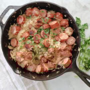 Kielbasa added back into the skillet with sauerkraut to finish cooking the dish.