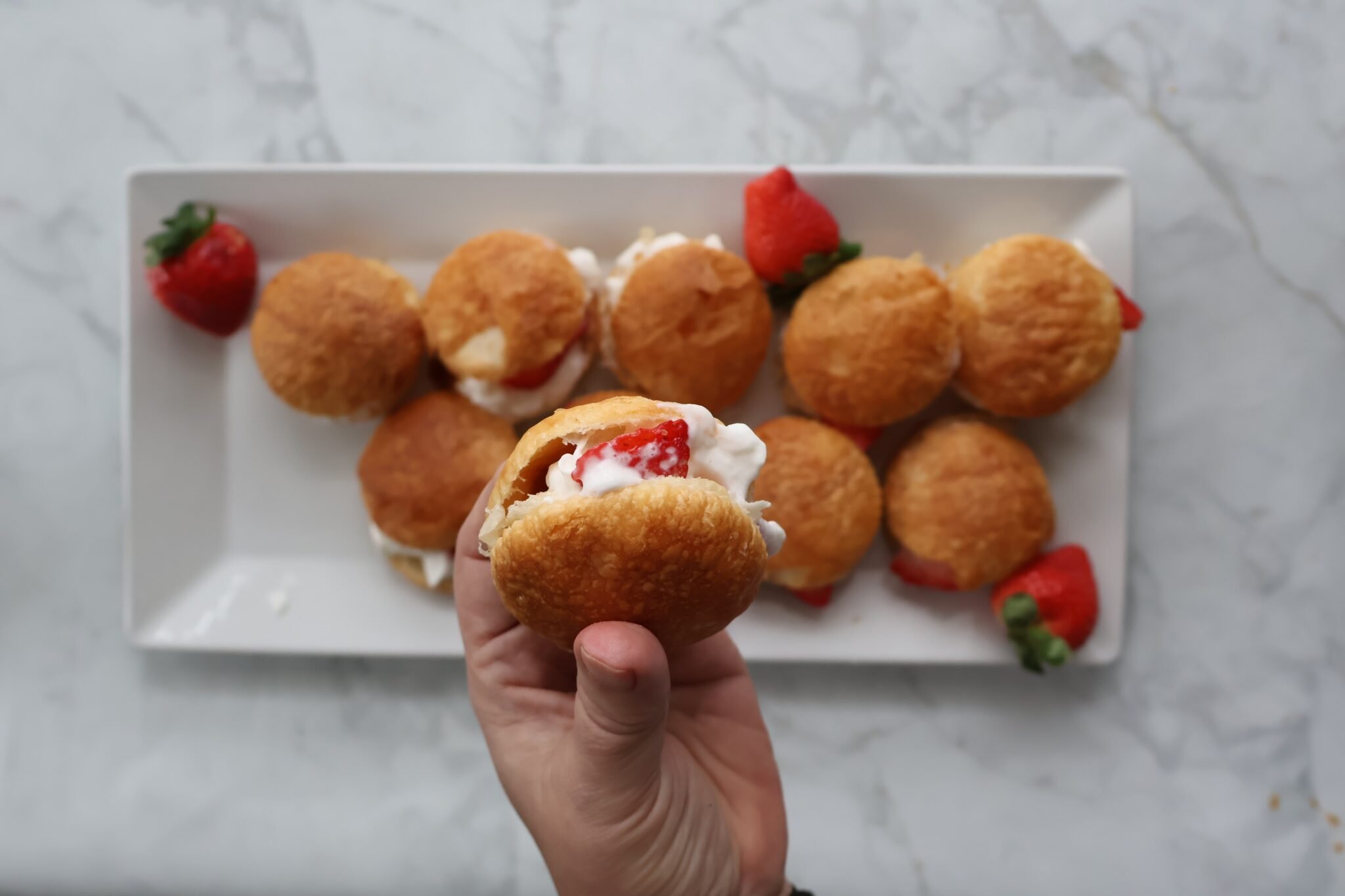 hand holding a strawberry cream puff