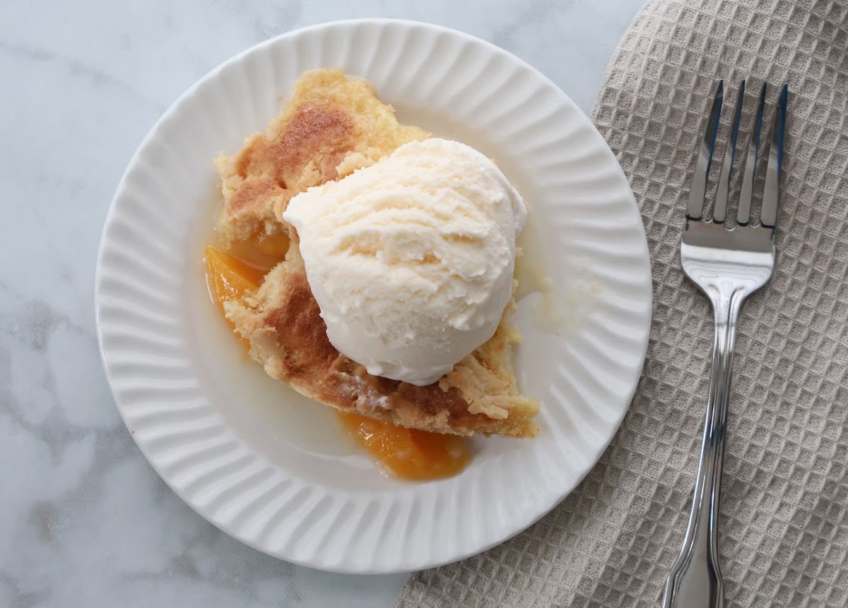 Dutch oven peach cobbler baked in a cast iron pot with golden cake mix topping and tender peach filling.