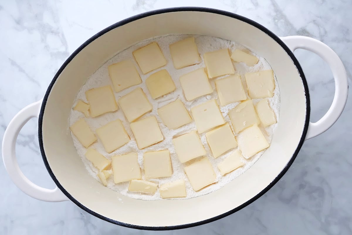 Butter placed over dry cake mix topping in dutch oven peach cobbler before going into the oven.