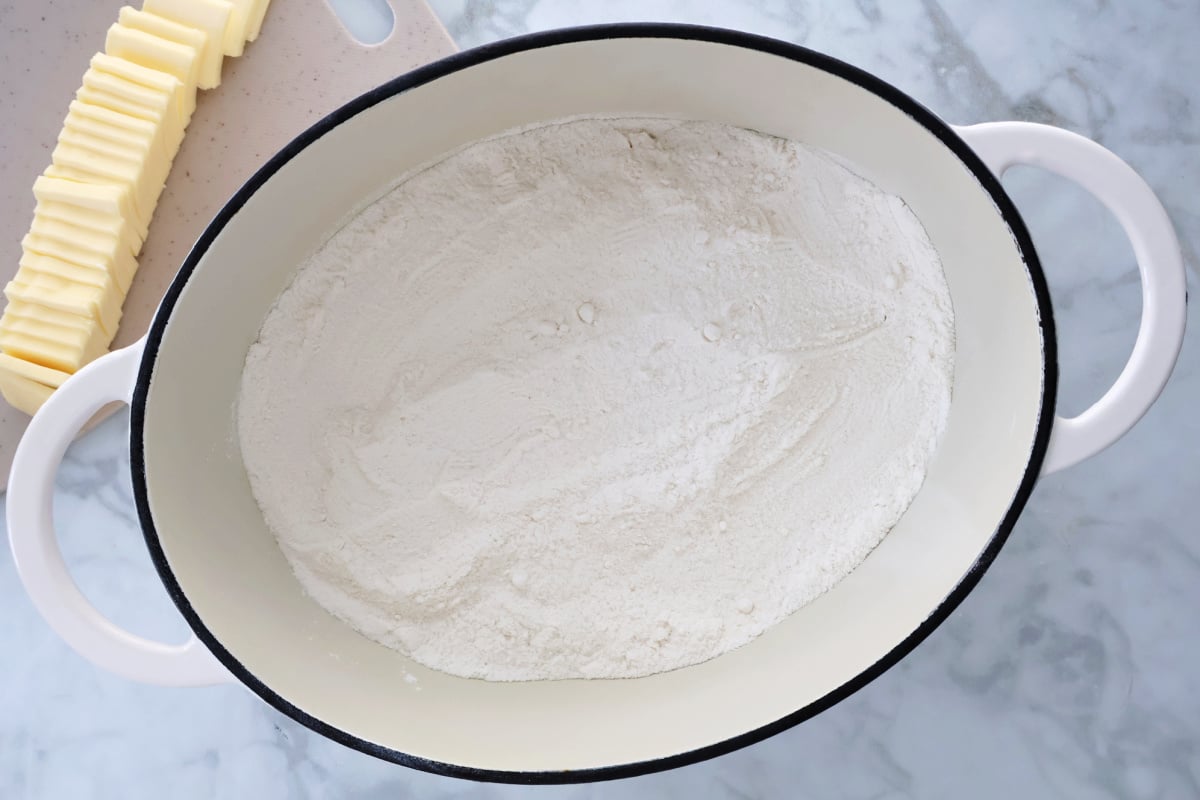 Cake mix layered over peaches in a cast iron dutch oven before baking peach cobbler.