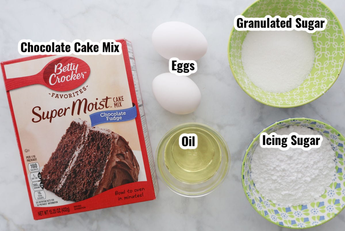 Ingredients for chocolate crinkle cookies including chocolate cake mix, eggs, oil, granulated sugar and powdered sugar.