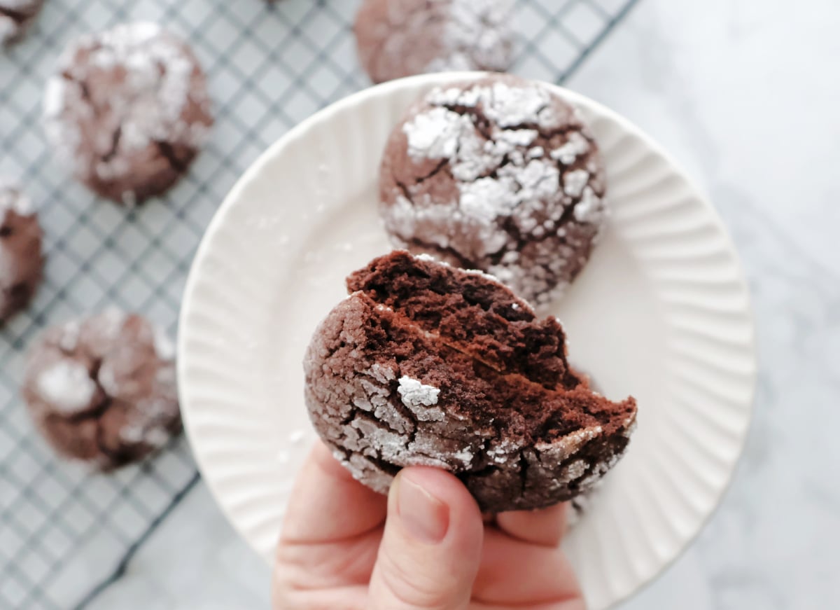 Chocolate crinkle cookie broken open showing soft brownie like center.