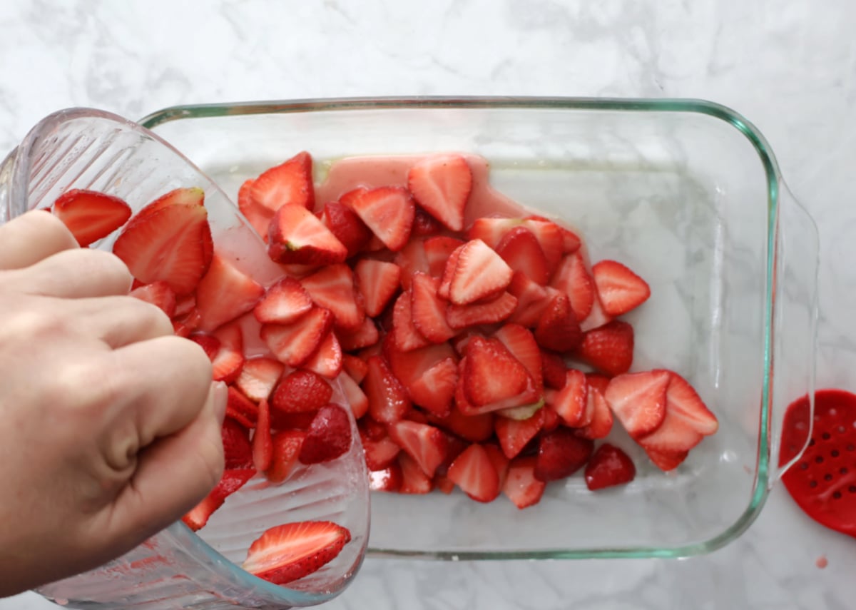 Layers of strawberries, cream cheese, and cake mix in baking dish before baking