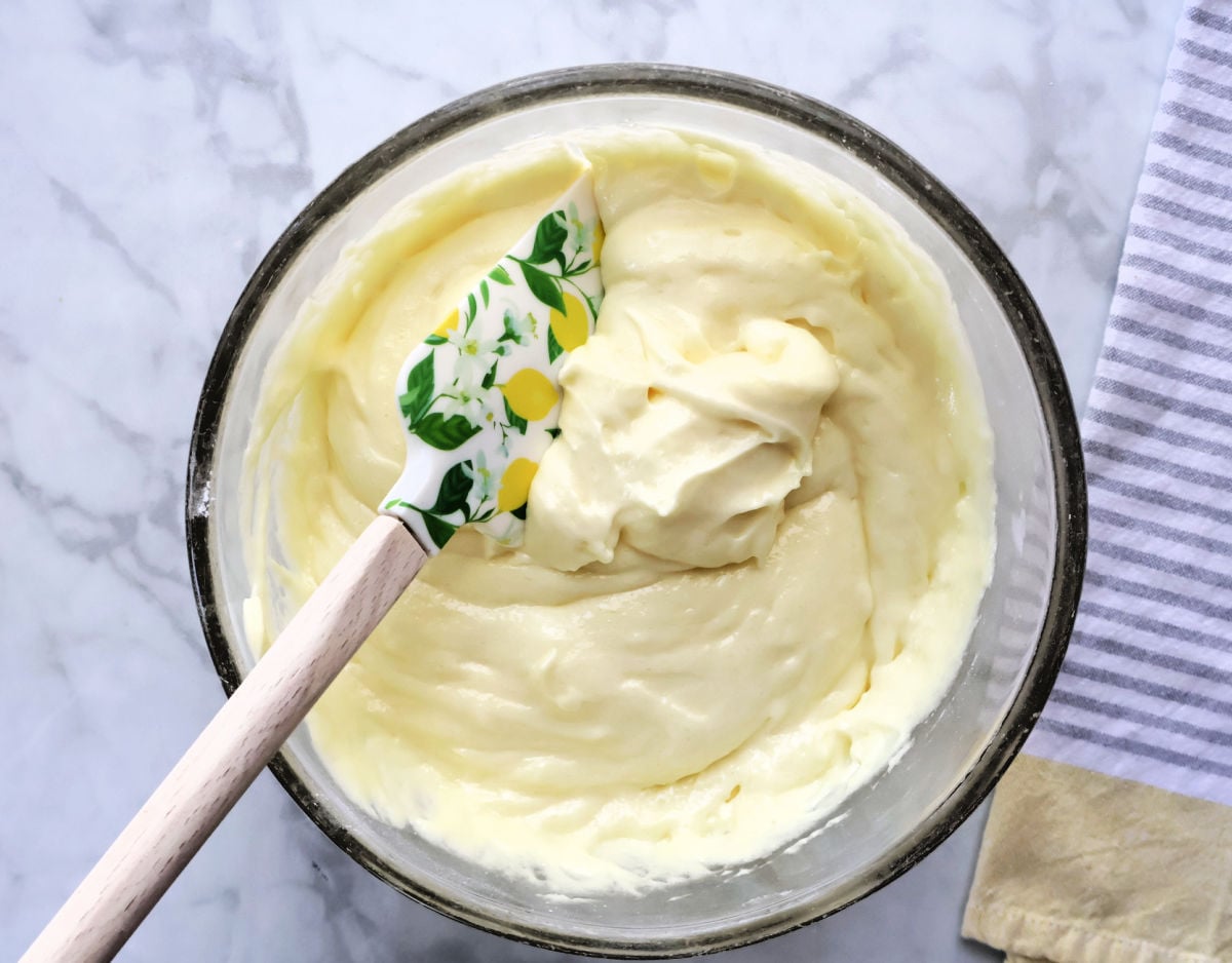 Lemon pie filling and angel food cake mix being stirred together in a large mixing bowl.