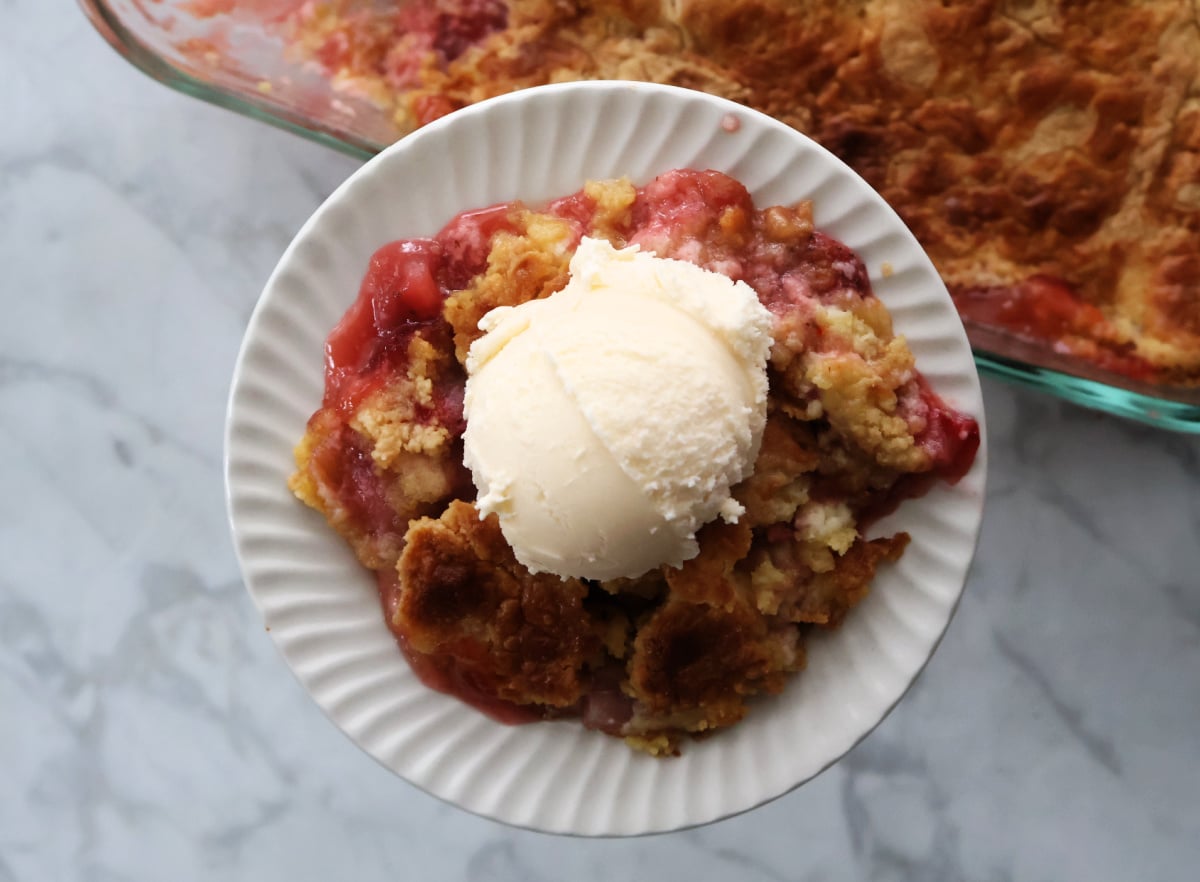 Slice of strawberry dump cake with cream cheese layer served on a white plate