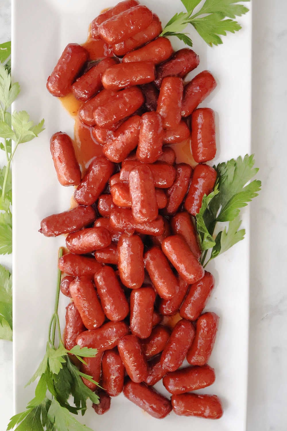 lil smokies with grape jelly on a white serving platter.